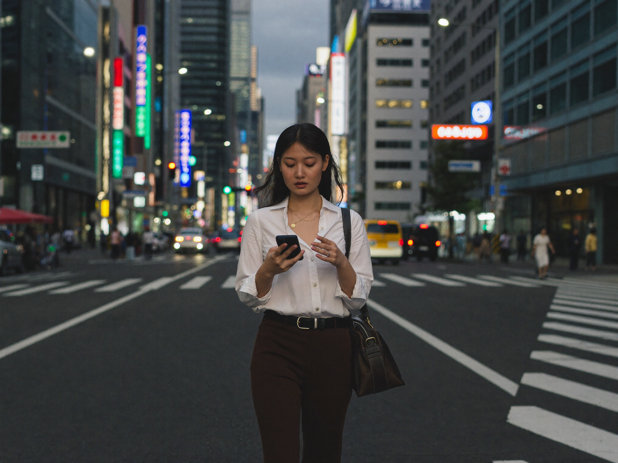 夕暮れの街でスマホを使う女性